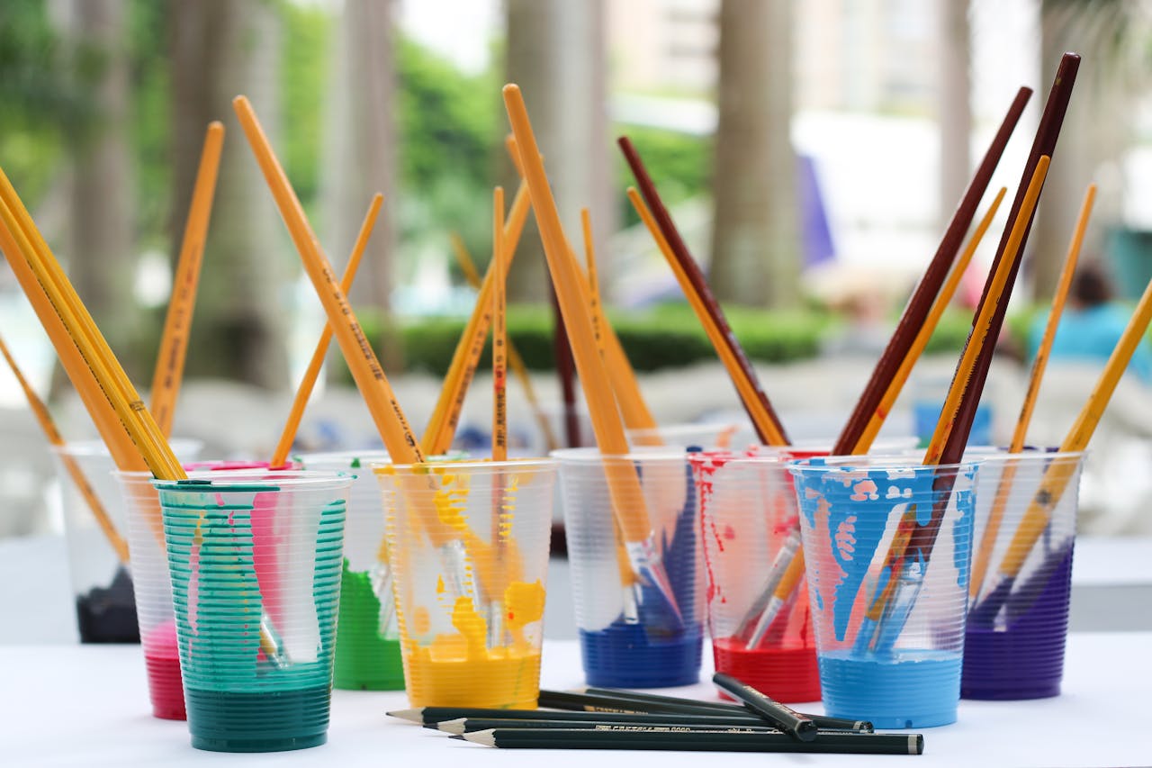 services-04 Vibrant paint brushes and pencils in plastic cups for arts and crafts.